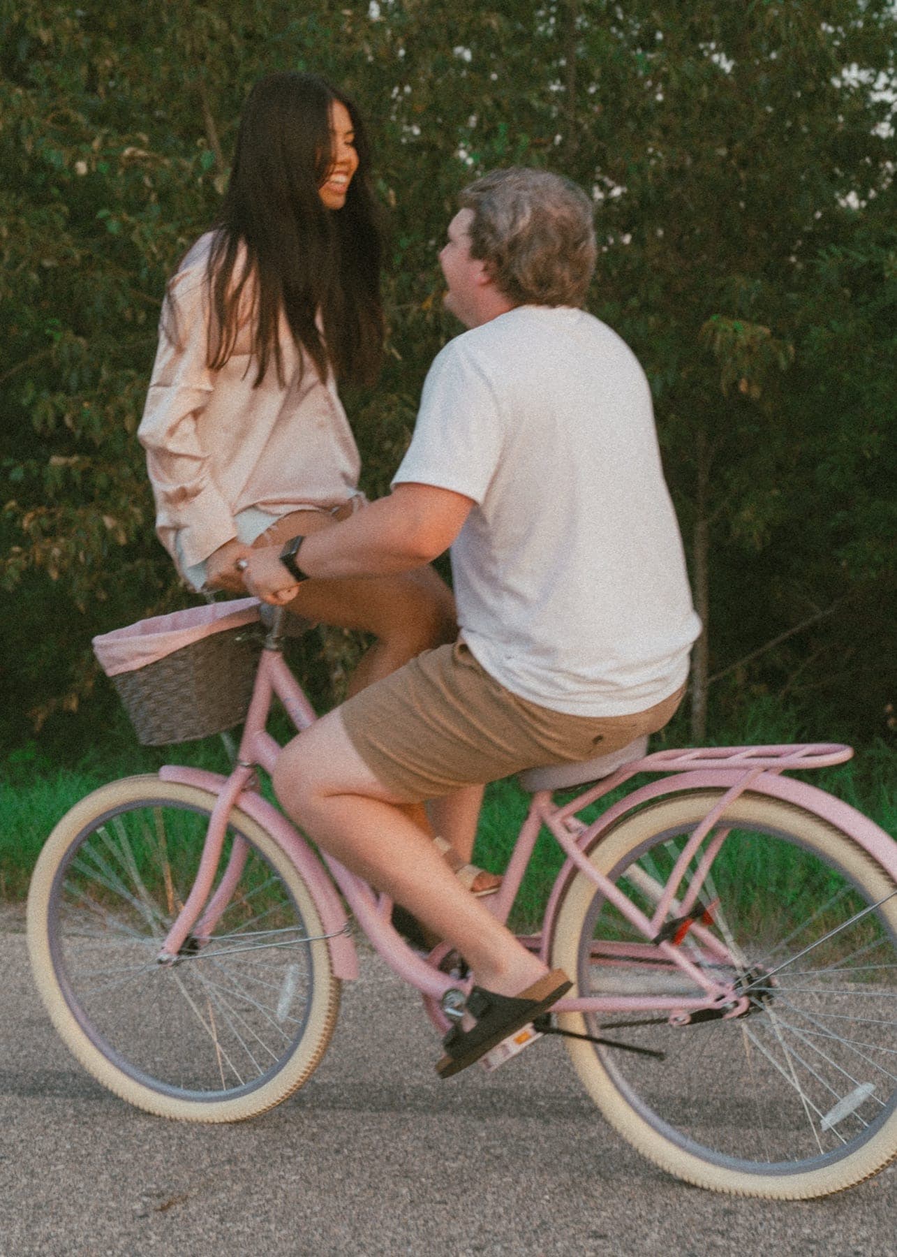 Couple laughing on a pink cruiser bike