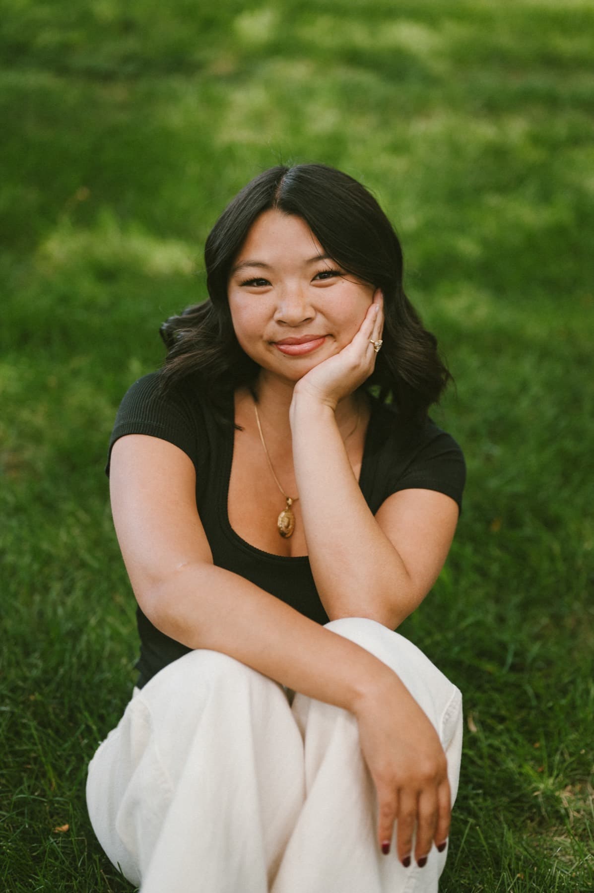 Portrait seated in the grass, chin resting on her hand