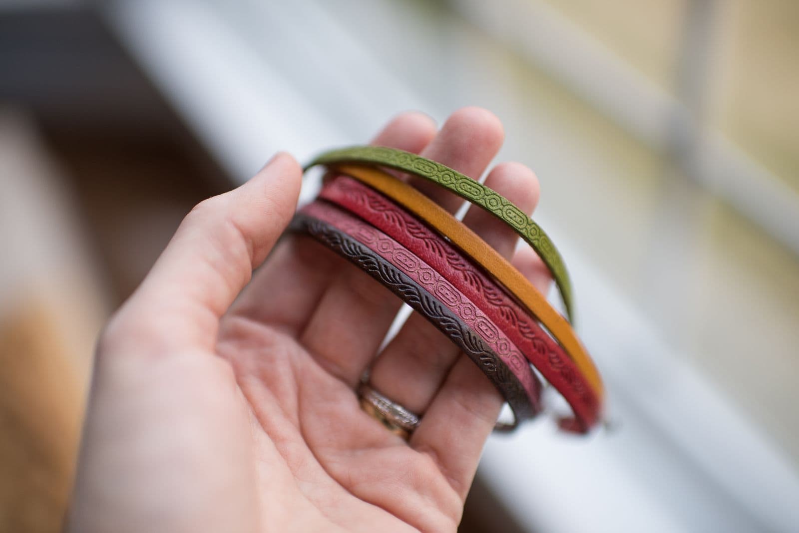 A hand holding a stack of colorful patterned bracelets